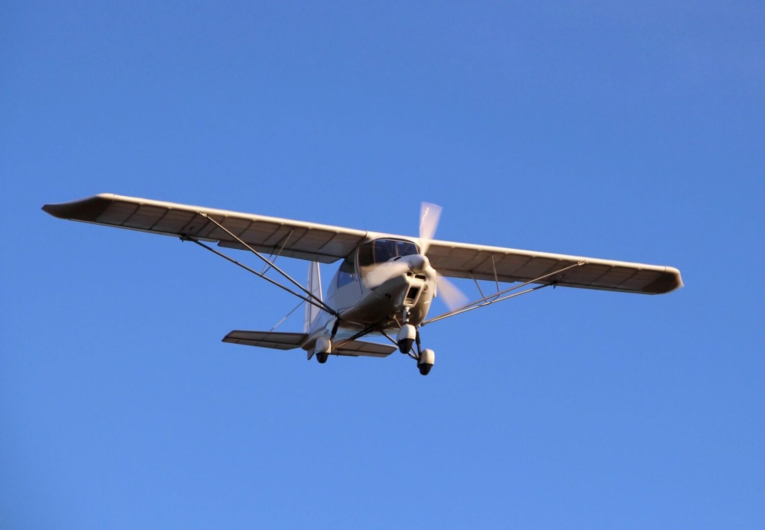 A small airplane flying in the sky with its landing gear down.