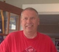 A man in red shirt smiling for the camera.